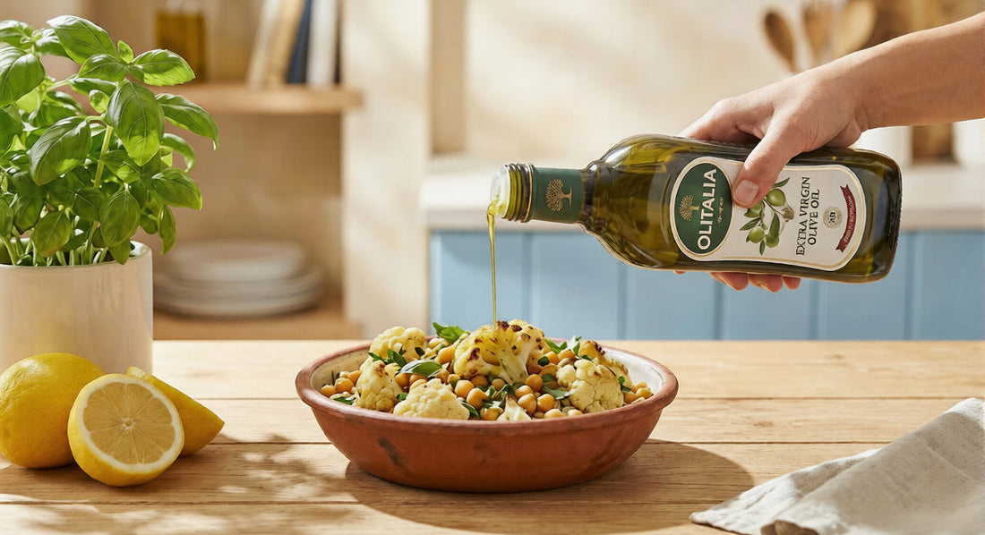 Golden Olitalia Extra Virgin Olive Oil being drizzled over a heart-healthy bowl of roasted chickpeas and cauliflower, garnished with fresh Italian herbs on a rustic wooden table.