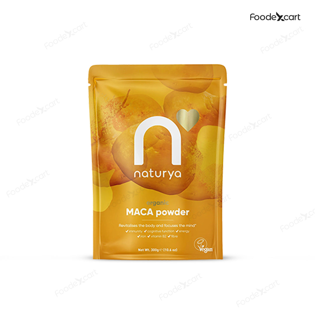Naturya Organic Maca Powder 300g pouch, showing the golden packaging with Maca root illustrations, a 'Vegan' logo, and key benefits listed: immunity, cognitive function, energy, iron, vitamin B2, and fibre. The bag is set against a white background with subtle Foodexcart watermarks